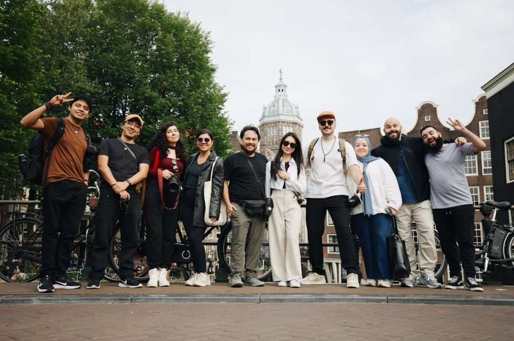 Diverse group of tourists posing in Amsterdam with a historic building backdrop.