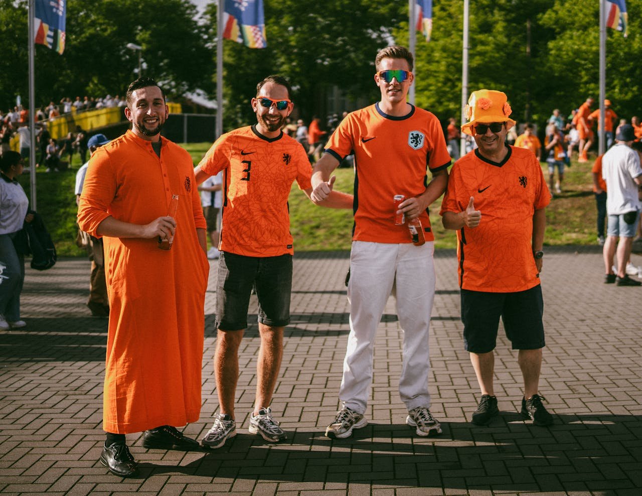 Four men in orange Dutch football jerseys enjoying a festive outdoor event.