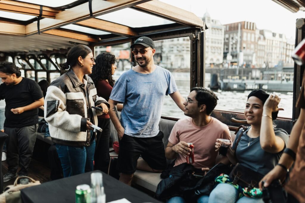 A lively group enjoys a sunny boat party cruising through the canals of Amsterdam.