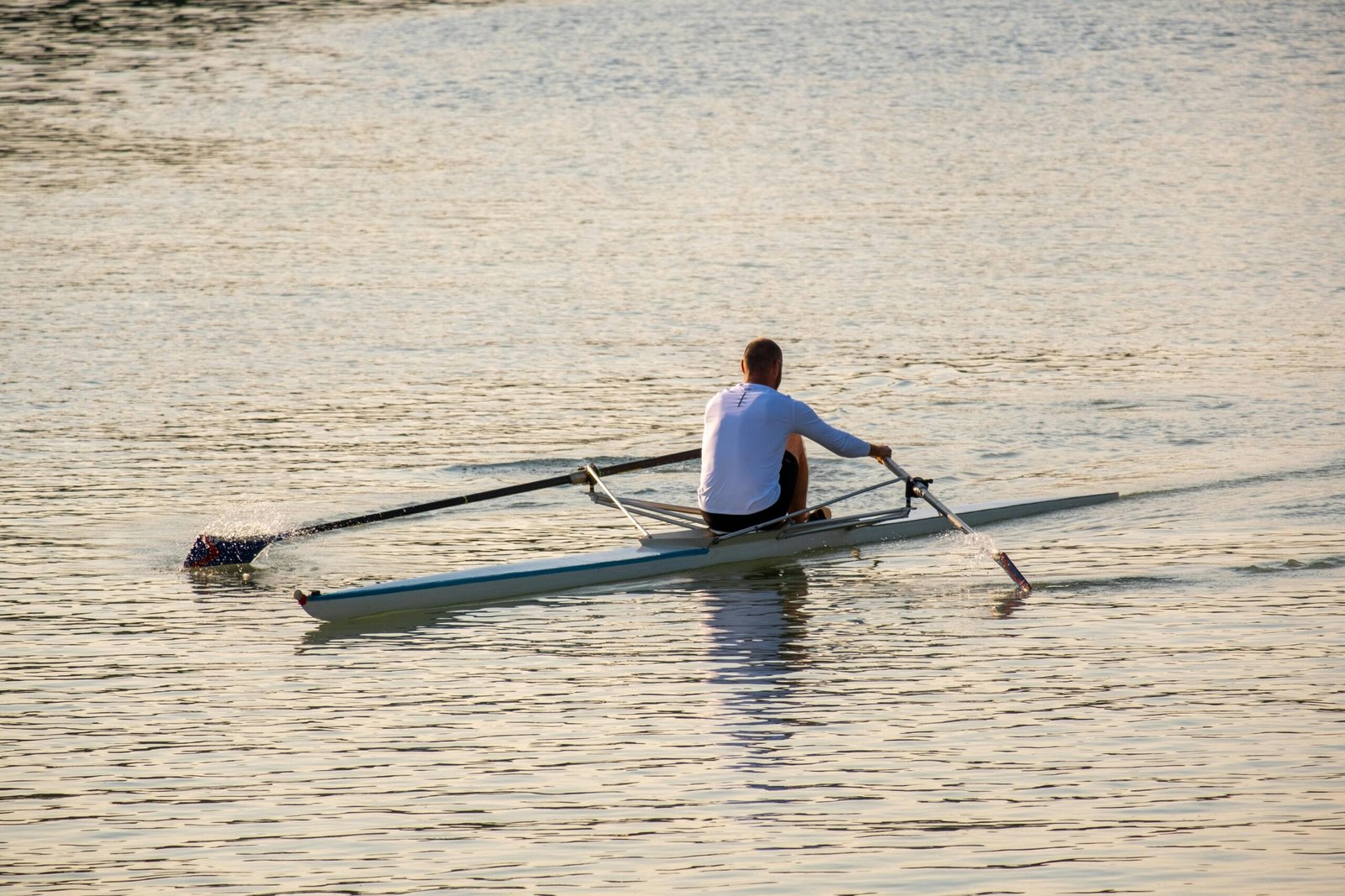 A man rowing a scull on the Danube River in Budapest at sunset, capturing a serene moment of leisure.